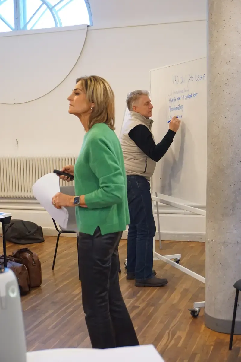 Två personer arbetar tillsammans vid en whiteboard under en workshop